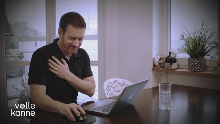 Mann fasst sich schmerzverzerrt an seine Schulter