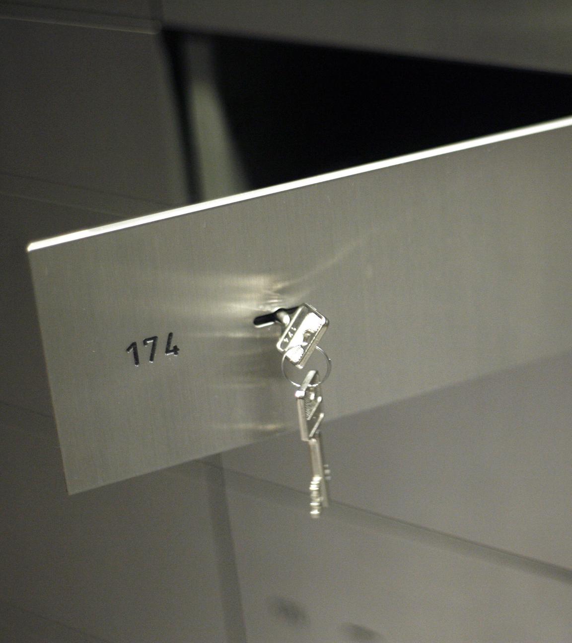 Ein Schließfach in einer Bank steht offen. An dem Fach hängt ein Schlüssel.