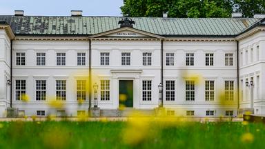 Die weitläufige Schlossanlage von Schloss Neuhardenberg erstreckt sich mit ihrem zentralen Hauptgebäude hinter einer Rasenfläche.