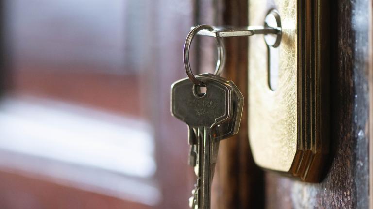 Ein Schlüssel steckt im Schloss einer Wohnungstür.