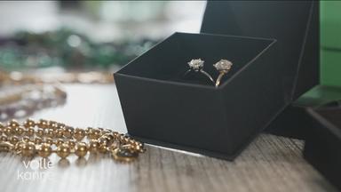 Zwei Silberringe und eine goldene Perlenkette liegen auf einem Tisch.