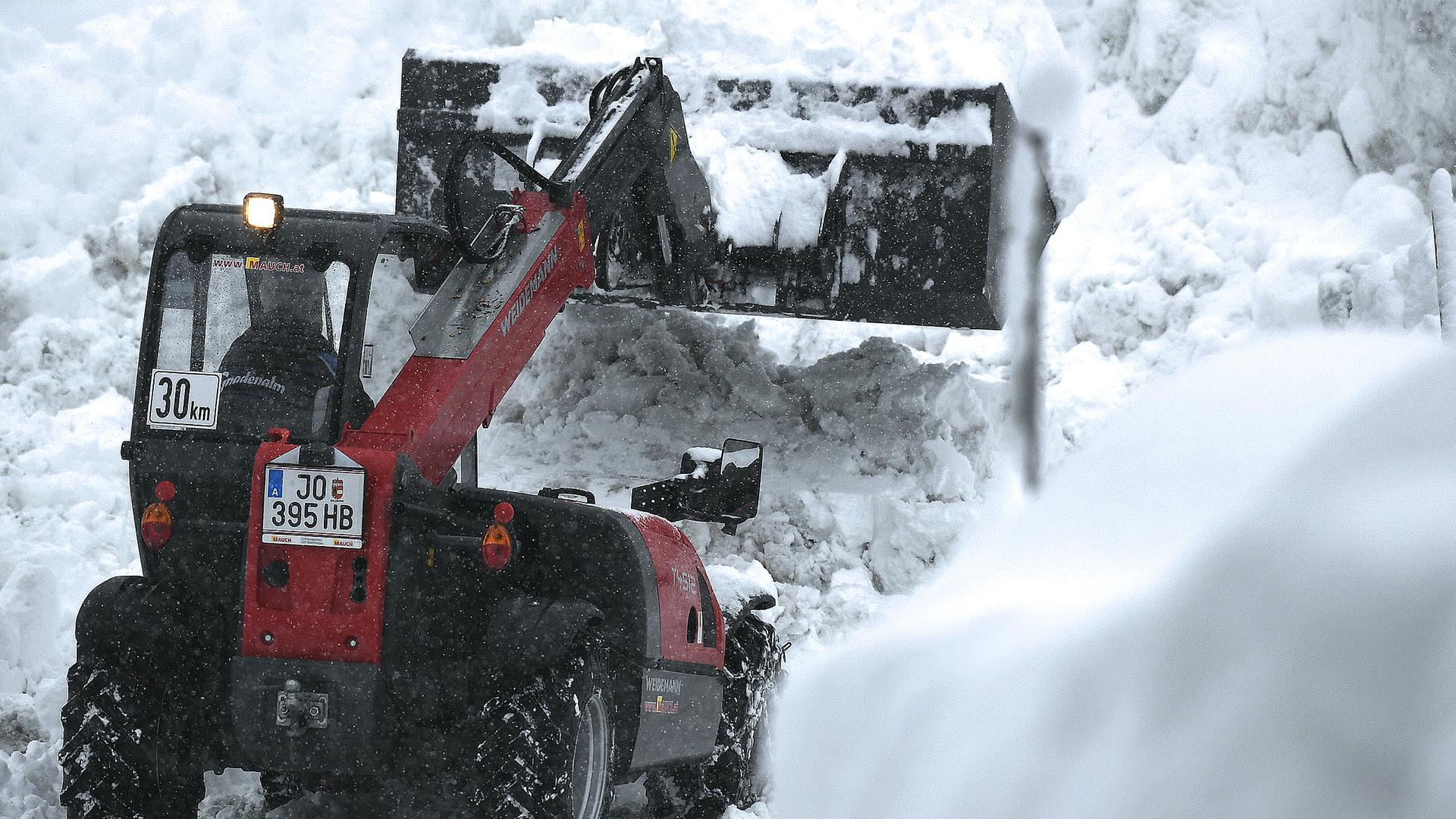 Ein Bagger befreit eine Straße vom Schnee.
