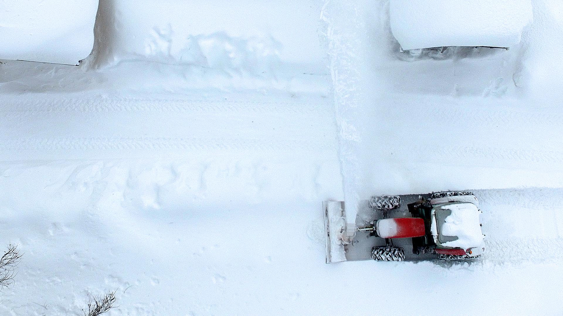 Die Luftaufnahme zeigt einen Schneepflug beim Räumen einer Straße.