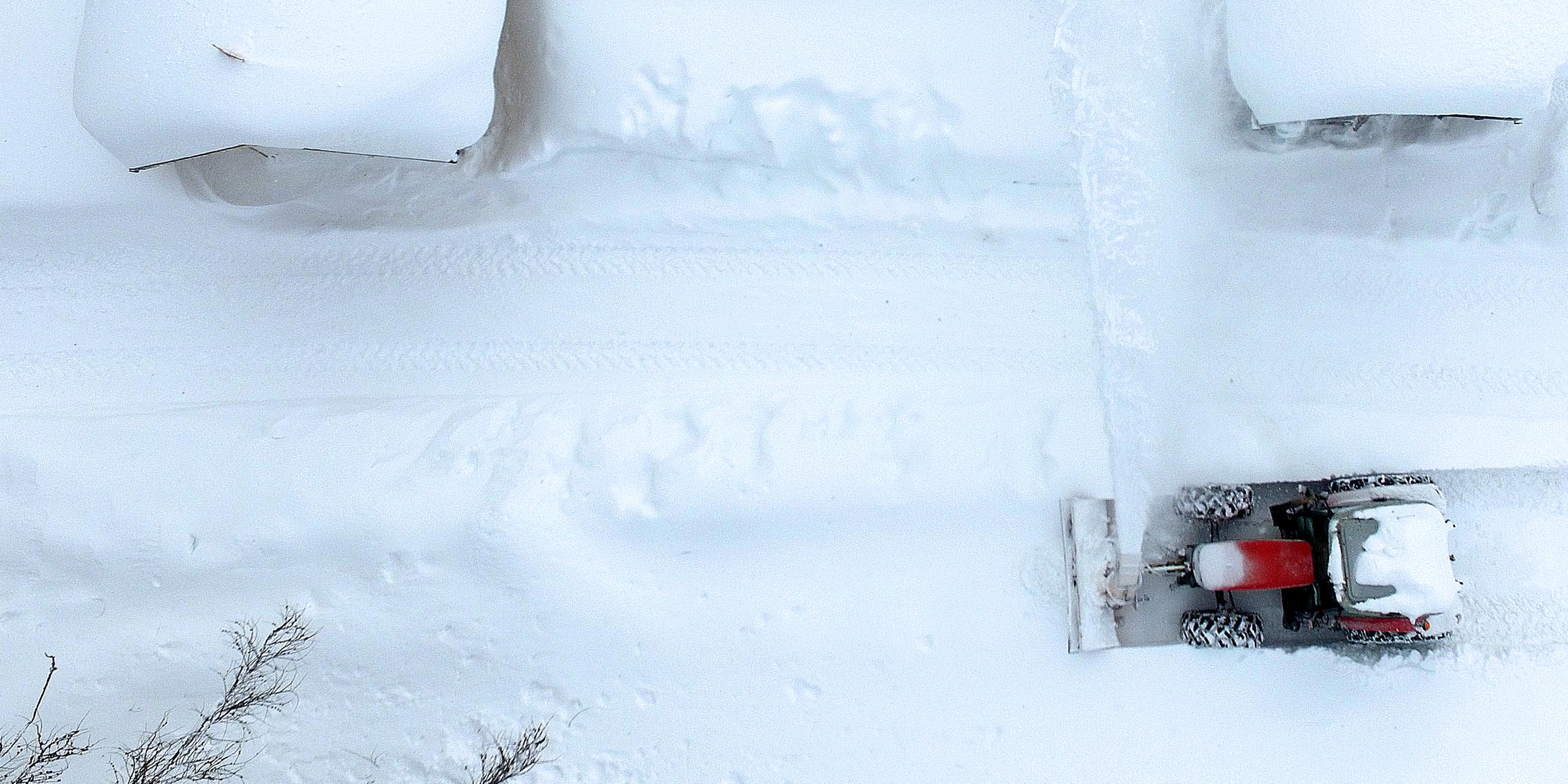 Die Luftaufnahme zeigt einen Schneepflug beim Räumen einer Straße.