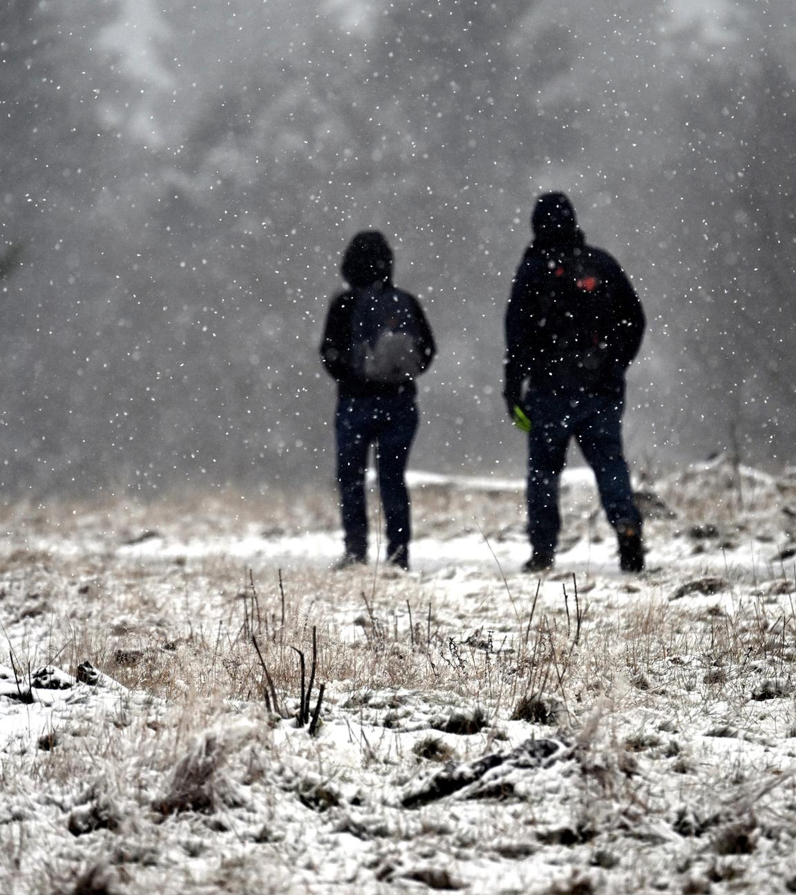 Zwei Wanderer gehen auf dem Kahlen Asten durch die Schneelandschaft. 