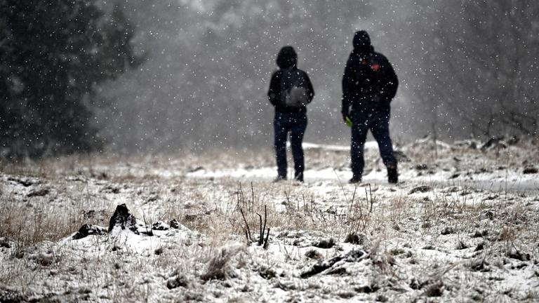 Zwei Wanderer gehen auf dem Kahlen Asten durch die Schneelandschaft. 