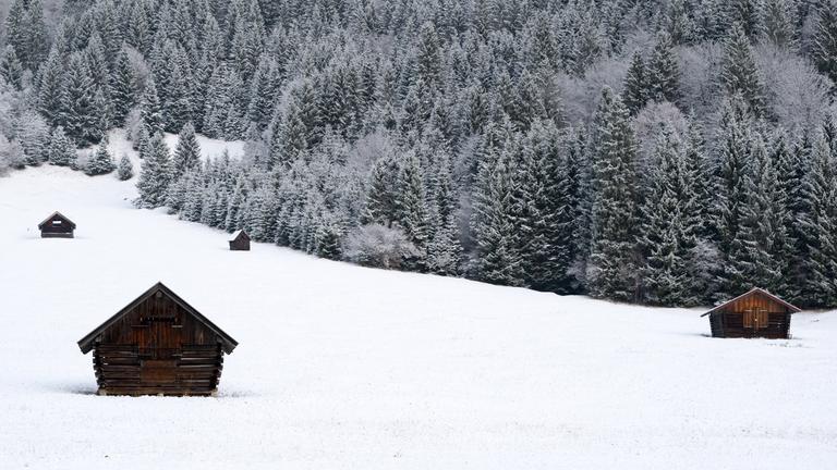 Heuschober stehen auf einer schneebedeckten Wiese (Bayern), aufgenommen am 18.11.2025