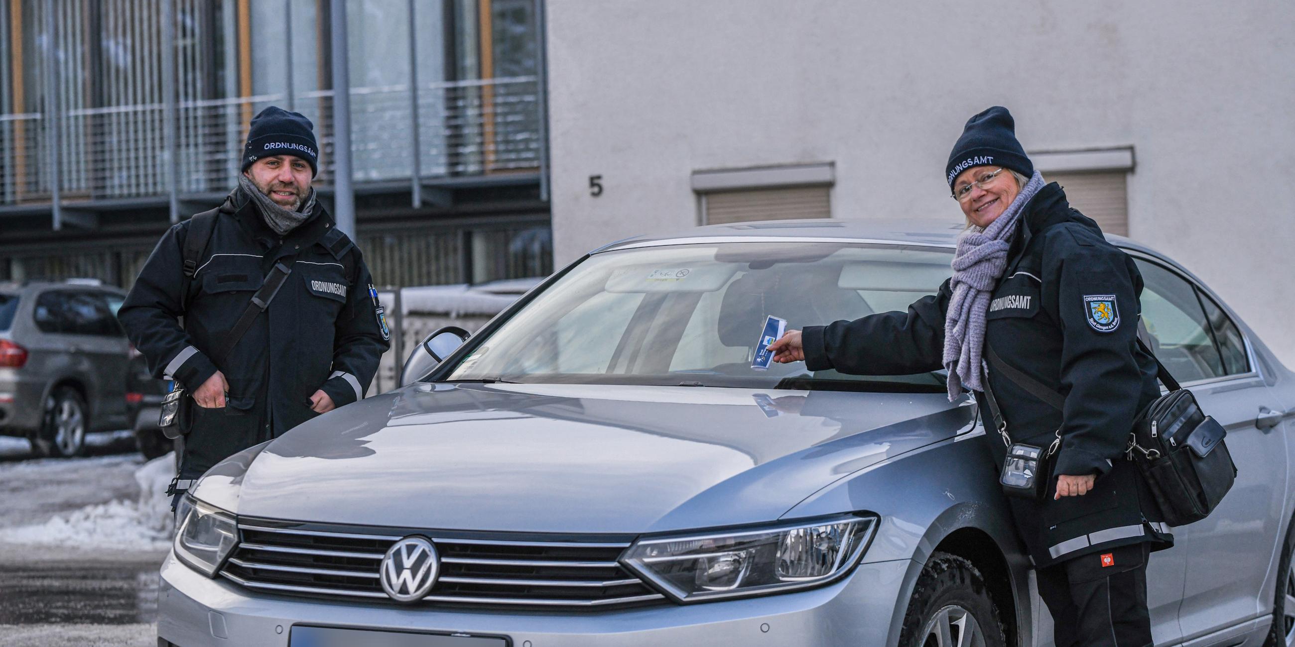 Zwei Mitarbeiter des Ordnungsamtes stehen auf einem Parkplatz in Giengen an der Brenz am 04.12.2023.