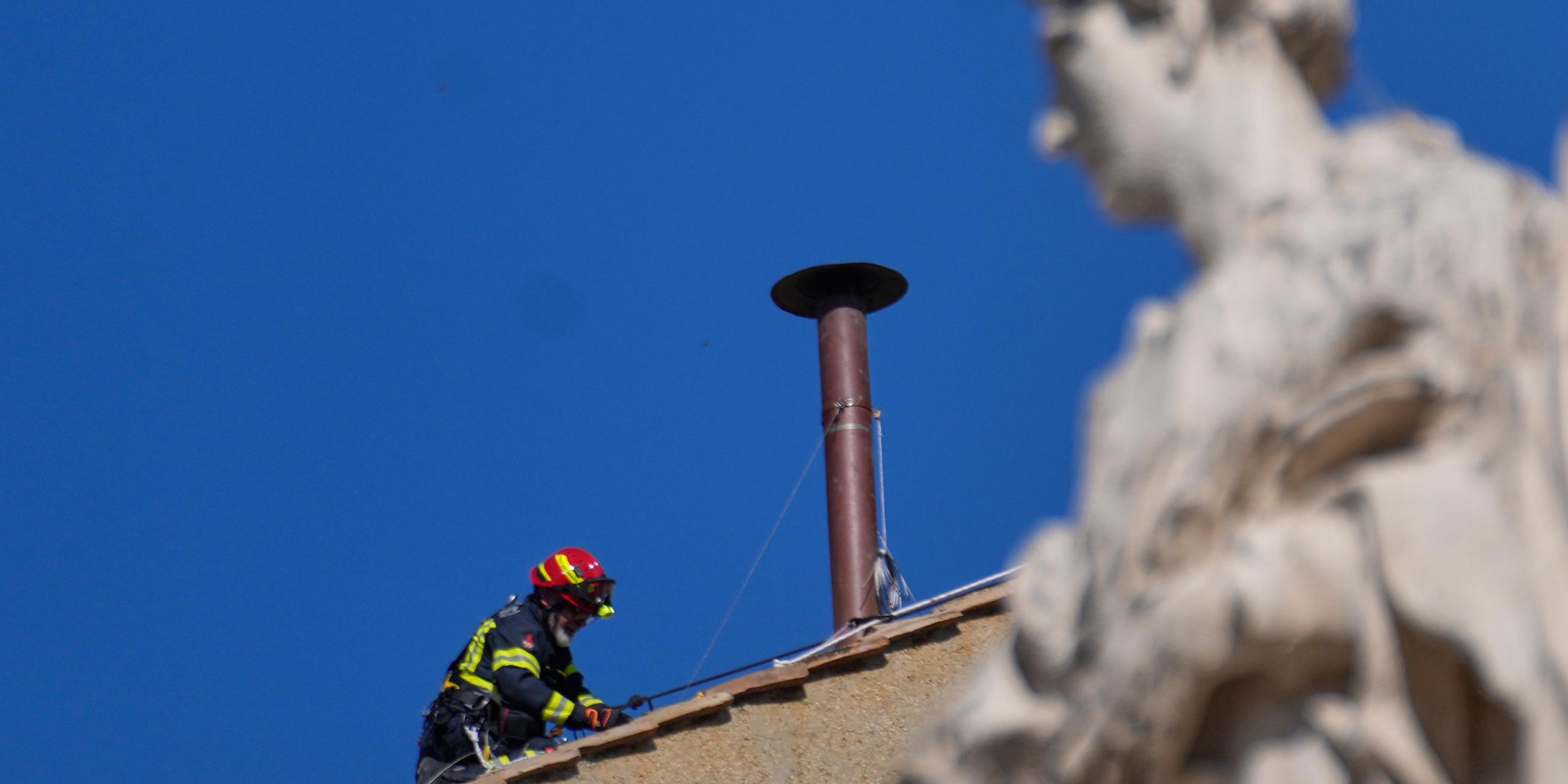 Ein Feuerwehrmann platziert den Schornstein fürs Konklave auf dem Dach der Sixtinischen Kapelle.