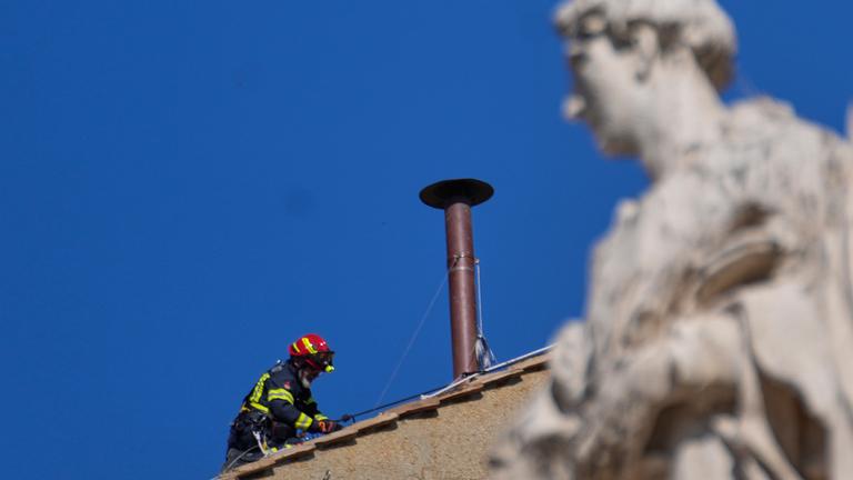 Ein Feuerwehrmann platziert den Schornstein fürs Konklave auf dem Dach der Sixtinischen Kapelle.