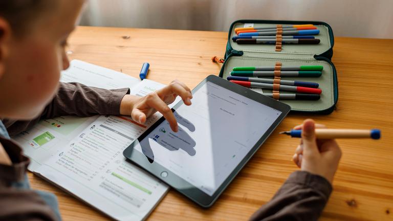 Ein Junge macht mithilfe eines Tablets zu Hause Hausaufgaben an seinem Schreibtisch. (Symbolfoto)