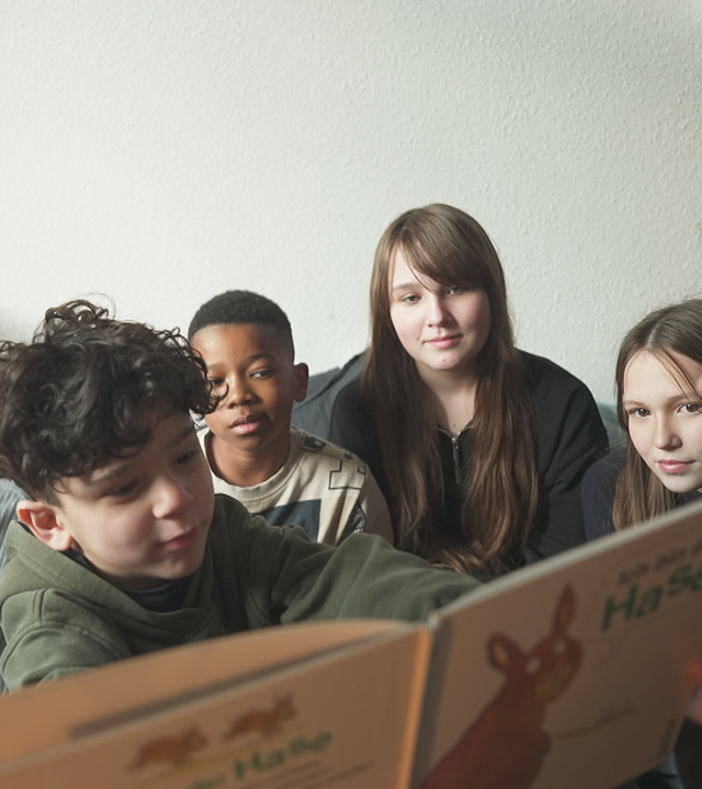 Schüler und Schülerinnen einer Bremer Gesamtschule sitzen zusammen und lesen gemeinsam ein Buch.