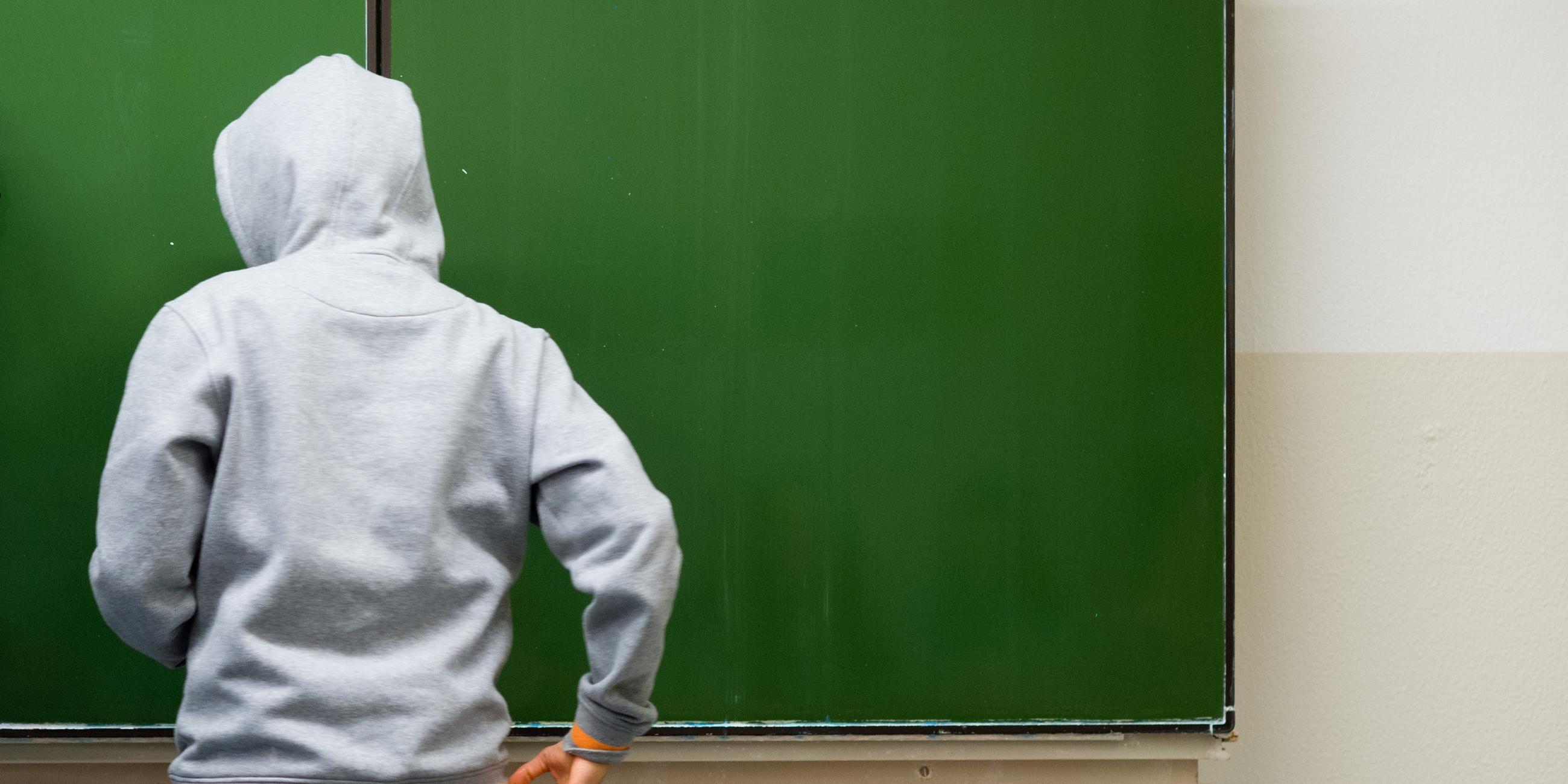 Schüler mit Kapuze an der Tafel