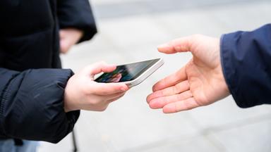 Ein Schüler gibt sein Handy ab.