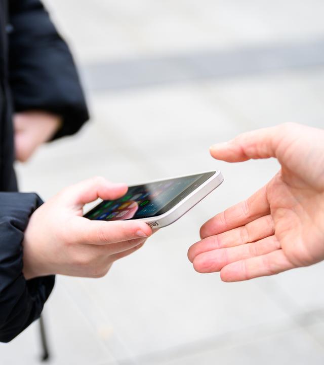 Ein Schüler gibt sein Handy ab.