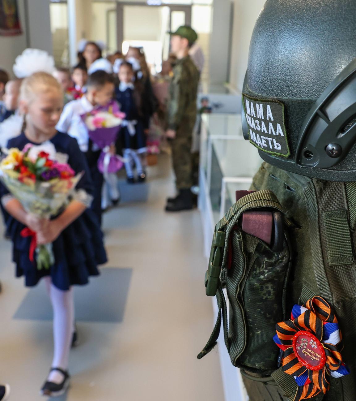 Eine Reihe von Kampfausrüstungen hängt zur Schau, während Schüler am Tag des Wissens, am 01.09.2025, zum Beginn des neuen Schuljahres in die Klasse der Sekundarschule Nr. 87 in Jekaterinburg, Russland, gehen.