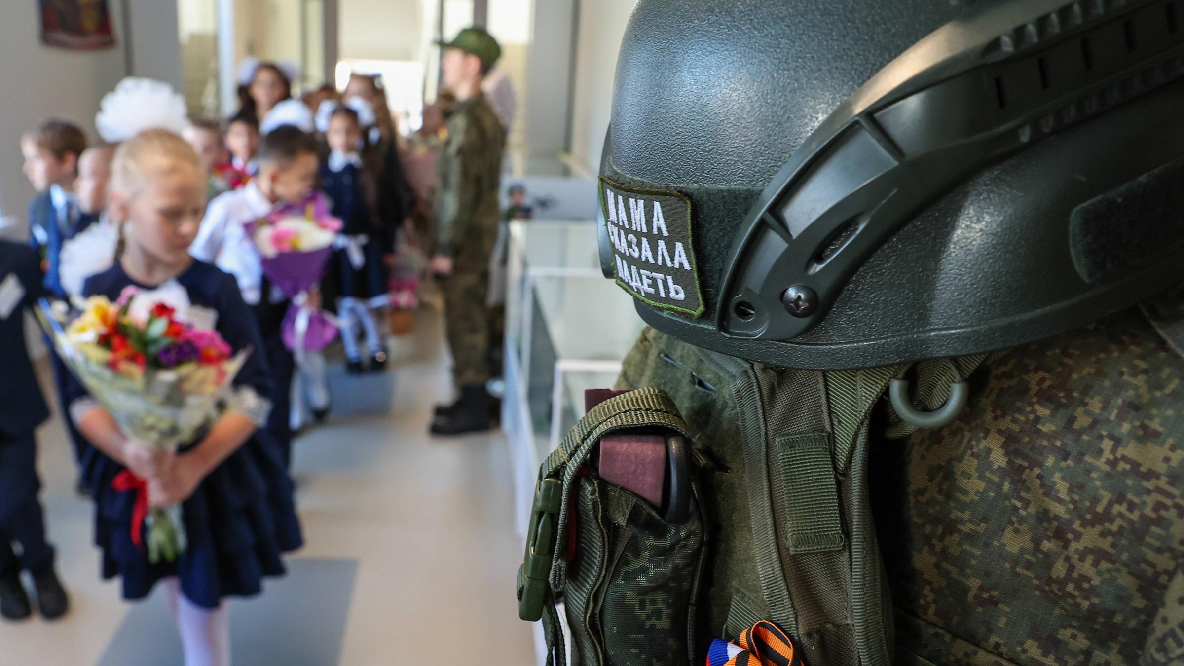 Eine Reihe von Kampfausrüstungen hängt zur Schau, während Schüler am Tag des Wissens, am 01.09.2025, zum Beginn des neuen Schuljahres in die Klasse der Sekundarschule Nr. 87 in Jekaterinburg, Russland, gehen.