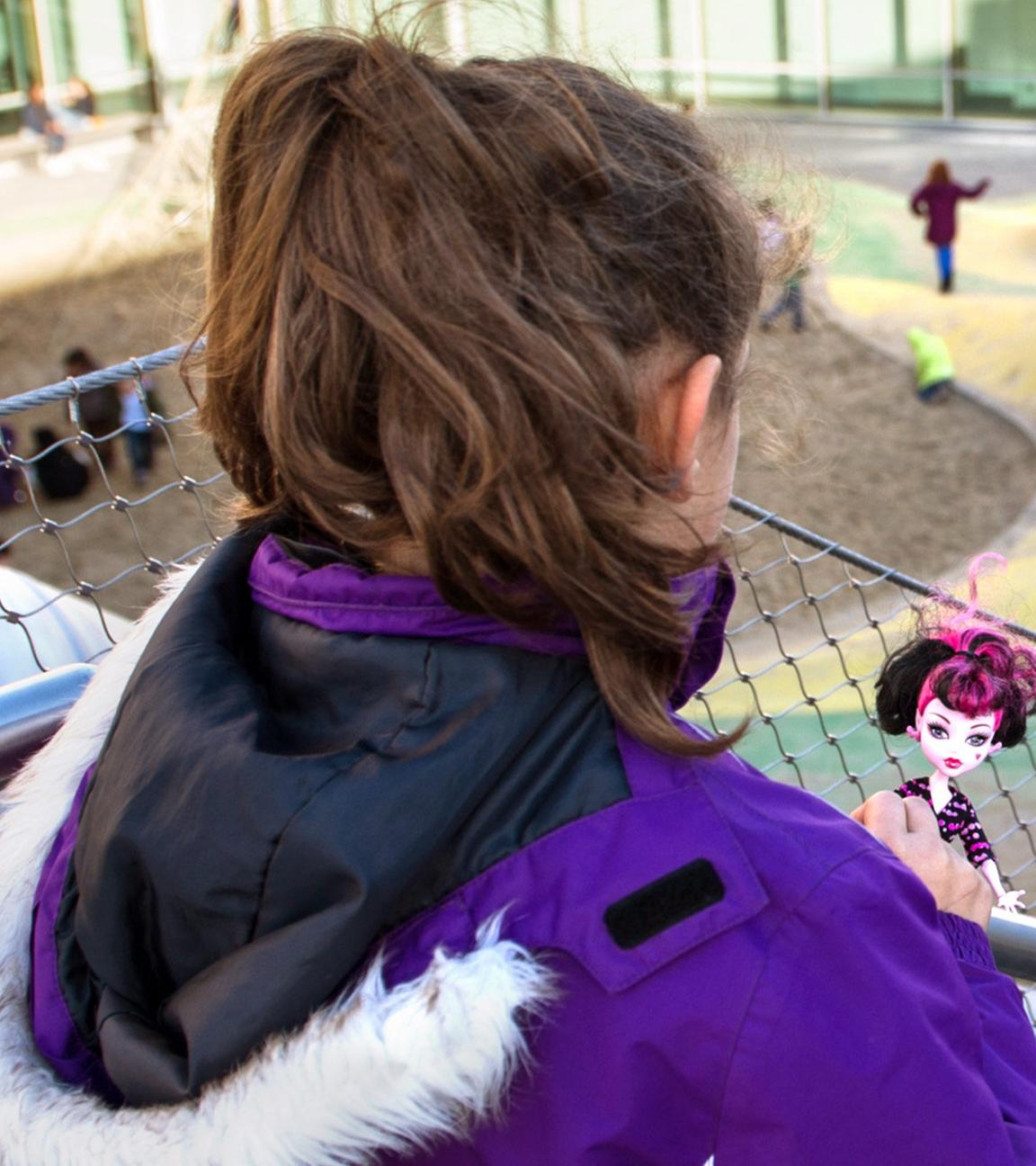Eine Schülerin beobachtet ihre Mitschüler auf dem Pausenhof.