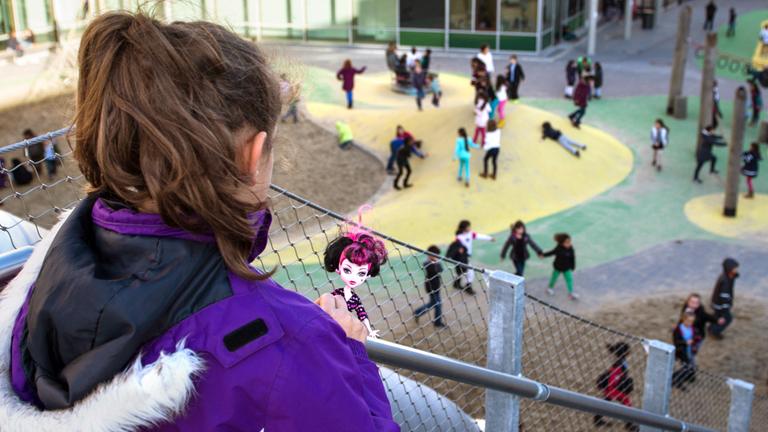 Eine Schülerin beobachtet ihre Mitschüler auf dem Pausenhof.