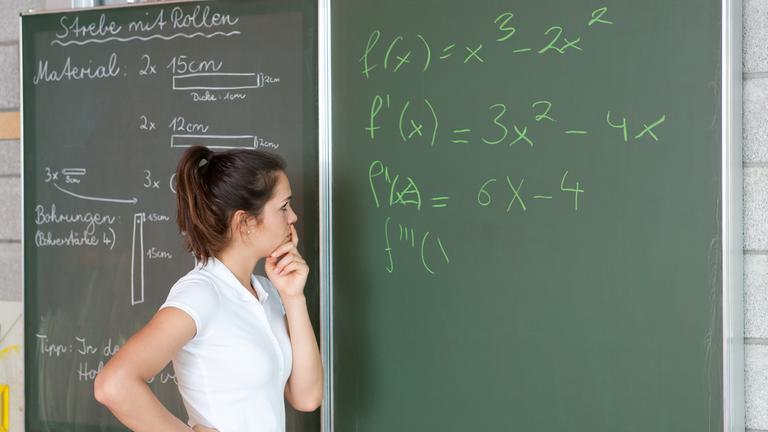 Schülerin bei schwieriger Matheaufgabe an der Tafel