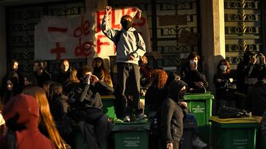 Schüler demonstrieren vor ihrer Schule, indem sie den Eingang zum Gebäude mit Mülltonnen versperren. 