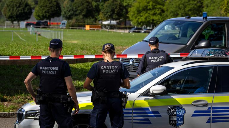 Drei Schweizer Kantonspolizisten sichern das Areal um die Pferderennbahn in Aarau, wo der Rave stattgefunden hatte.