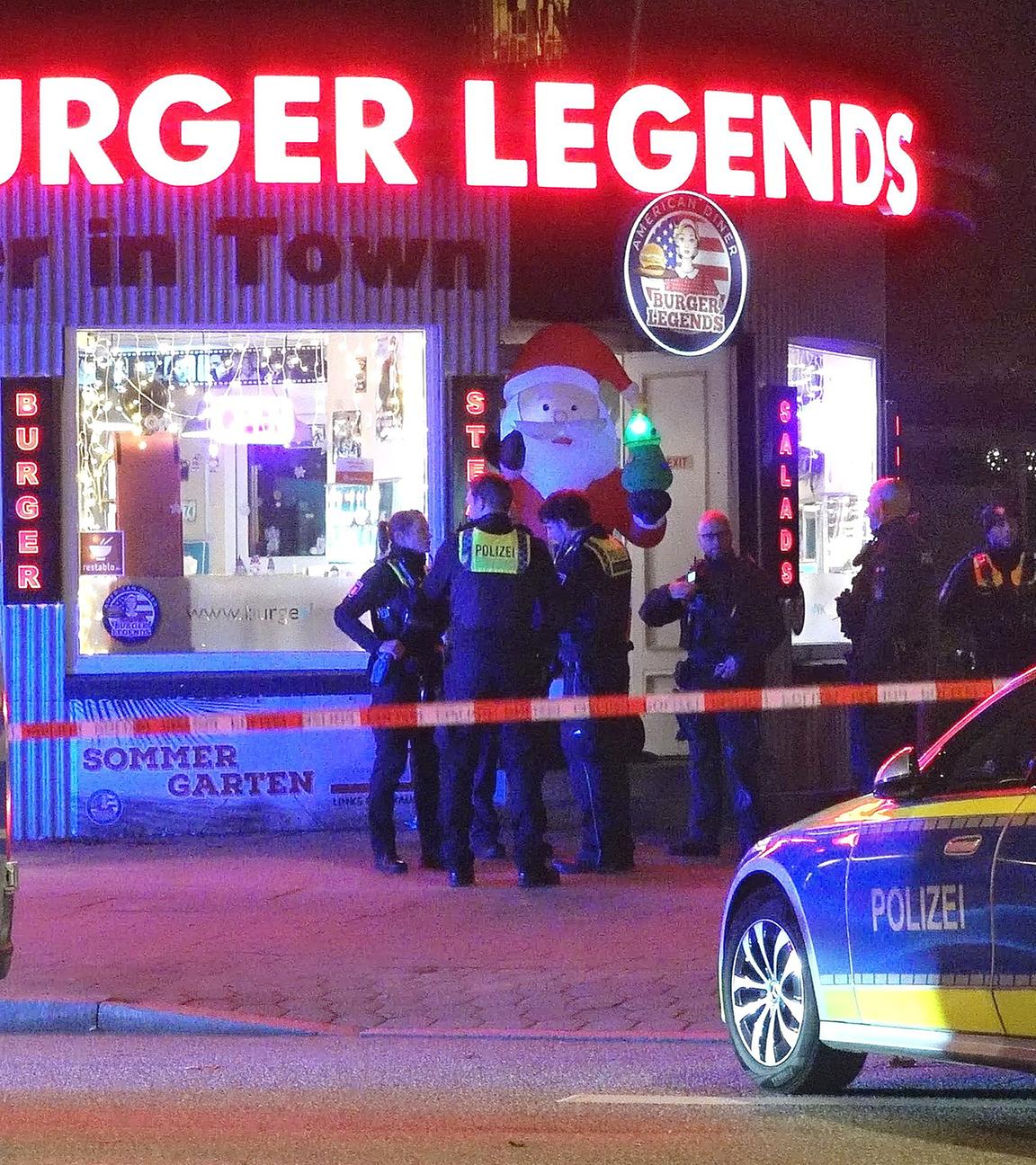 Einsatzkräfte der Polizei stehen vor dem Tatort, einem Burgerladen im Hamburger Bezirk Eimsbüttel, aufgenommen am 02.12.2025