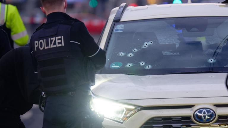 Ein Taxi mit Schusslöchern in der Frontscheibe steht auf der Straße. Vermutlich durch Schüsse soll in der Düsseldorfer Innenstadt ein Mensch verletzt worden sein.