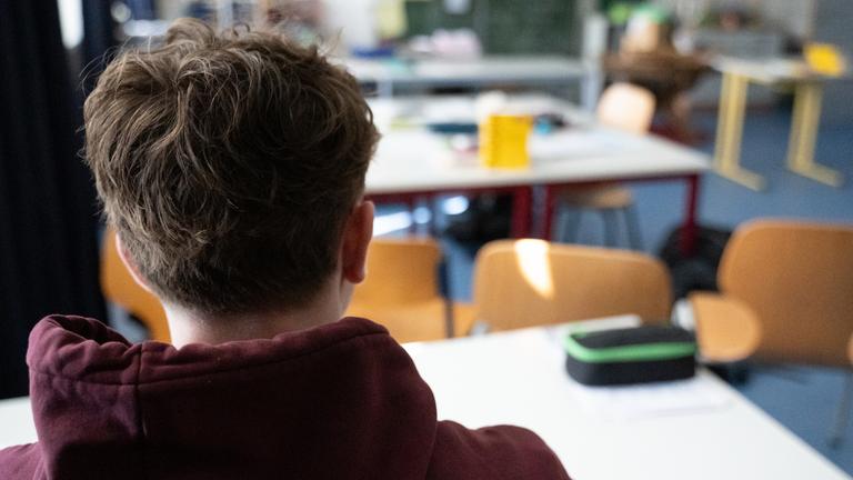 Ein Schüler sitzt an einem Tisch im Klassenzimmer einer Schule