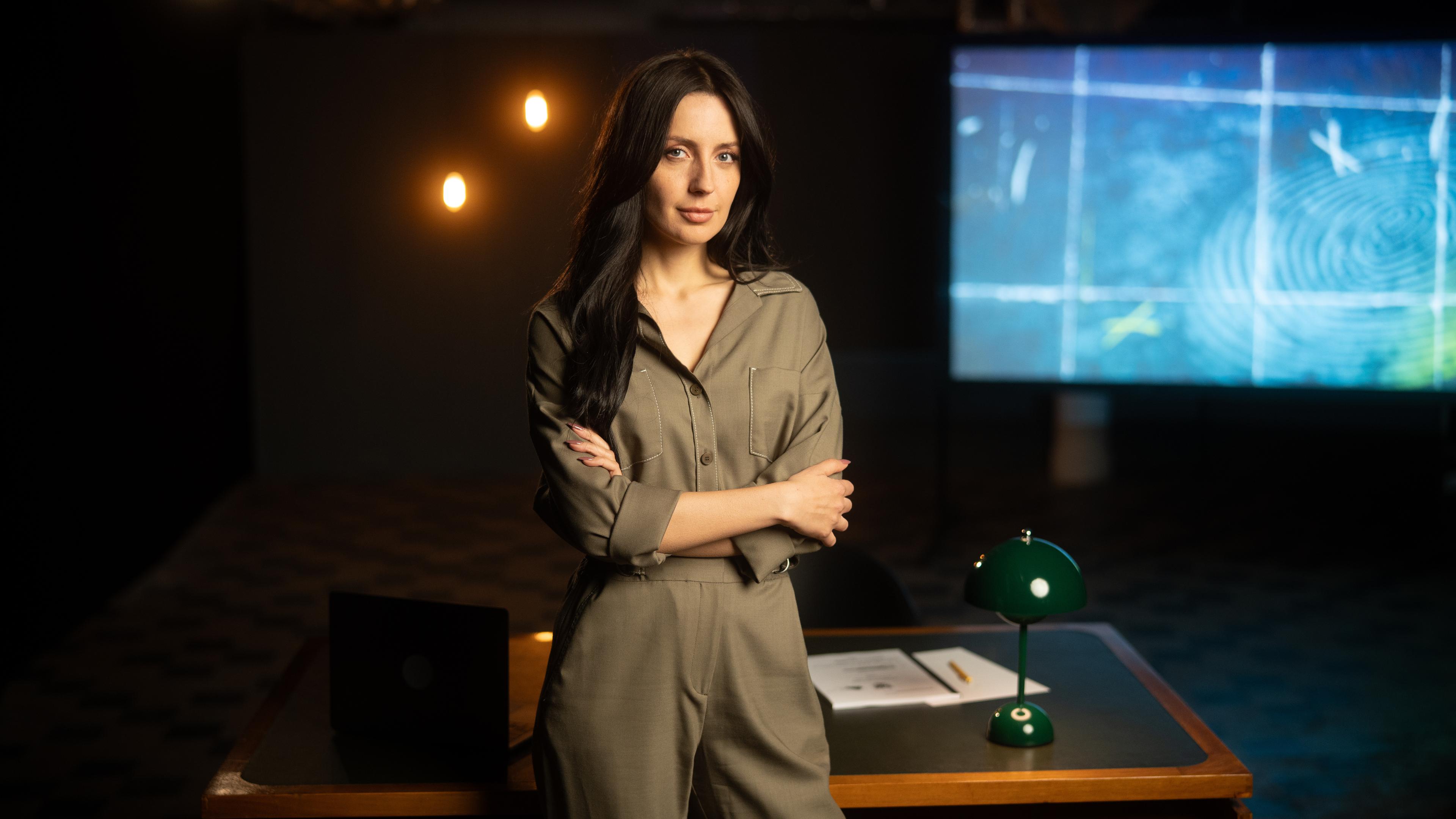 Paulina Krasa steht in einer Studiokulisse lächelnd mit verschränkten Armen vor einem Schreibtisch und blickt in die Kamera.