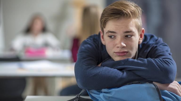 Ein Schlüer sitzt im Klassenzimmer und schaut besorgt.