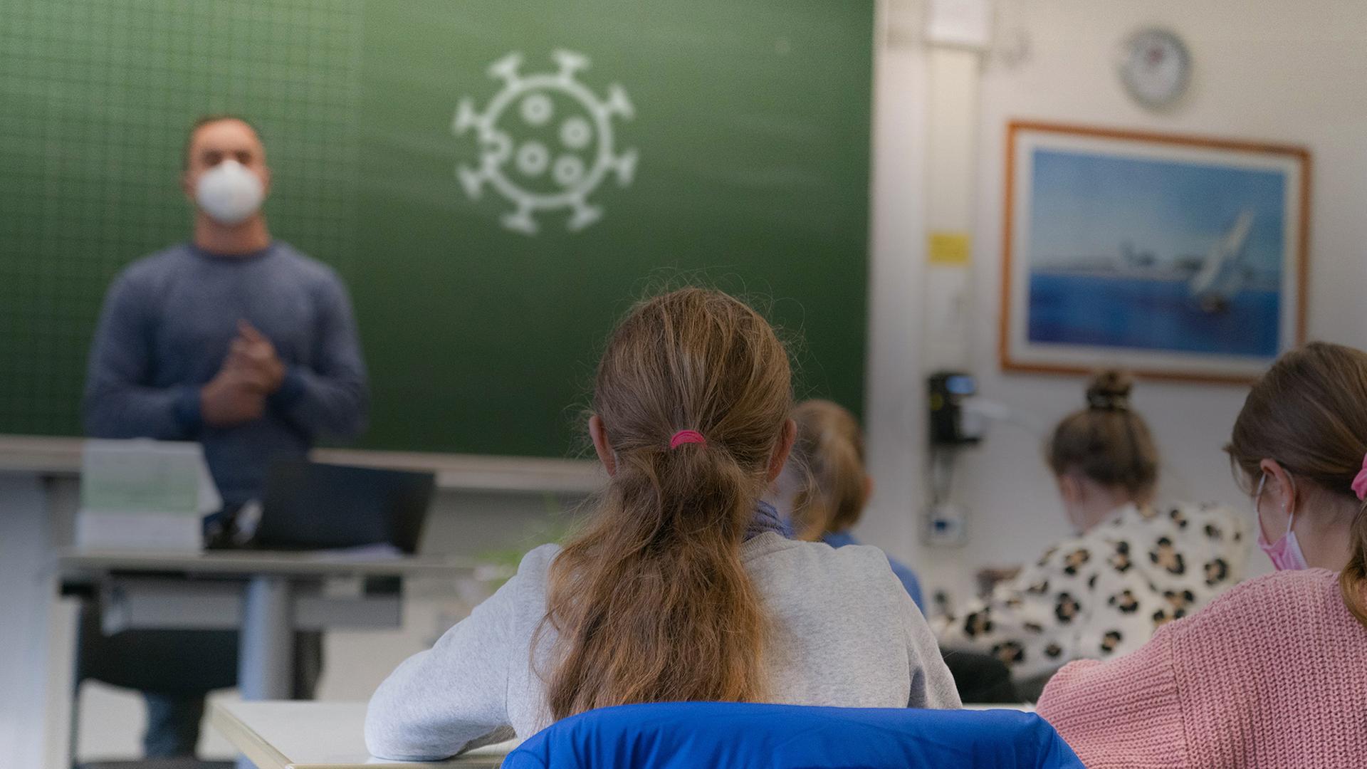 Ein Klassenzimmer mit einem Lehrer mit Maske, der an der Tafel steht, auf die das Corona-Symbol gezeichnet wurde. Im Vordergrund sieht man Kinder