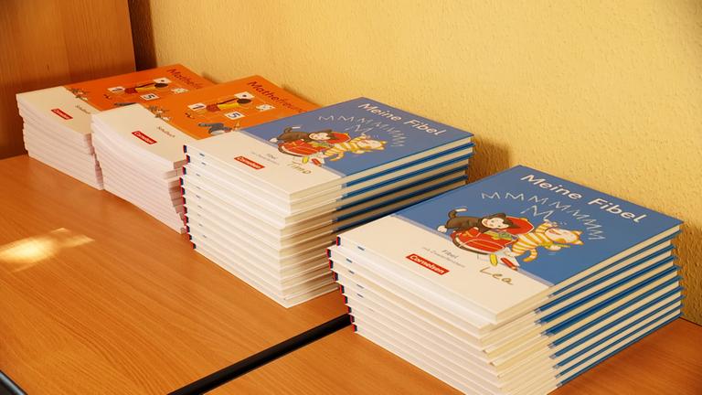 Auf einem Tisch liegen vier Stapel Schulbücher.