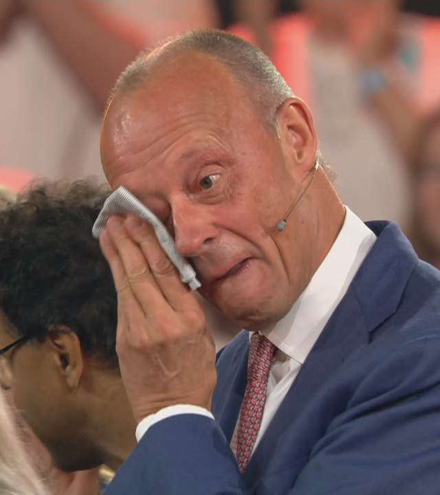 Bundeskanzler Merz wischt sich eine Träne aus dem Gesicht