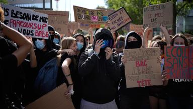 Ein Schüler hält ein Schild mit der Aufschrift "Wir wollen unterstützt und nicht überlastet werden" während einer Demonstration gegen unterfinanzierte Schulen vor einer Blockade vor einem Gymnasium.