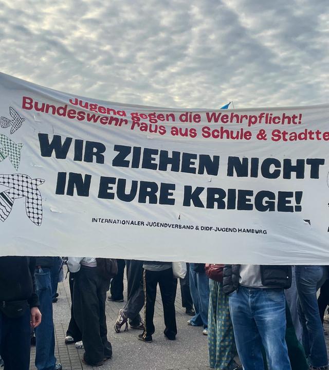 Hamburg: Menschen demonstrieren mit einem Banner mit der Aufschrift "Wir ziehen nicht in eure Kriege!" beim Schulstreik gegen die Wiedereinführung der Wehrpflicht.