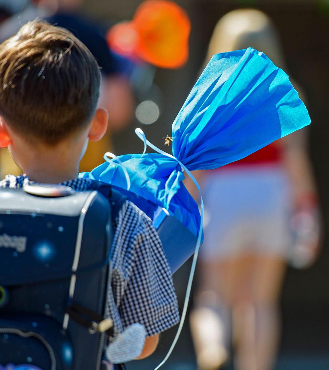 Ein Kind steht mit blauer Schultüte auf dem Schulhof in Remscheid