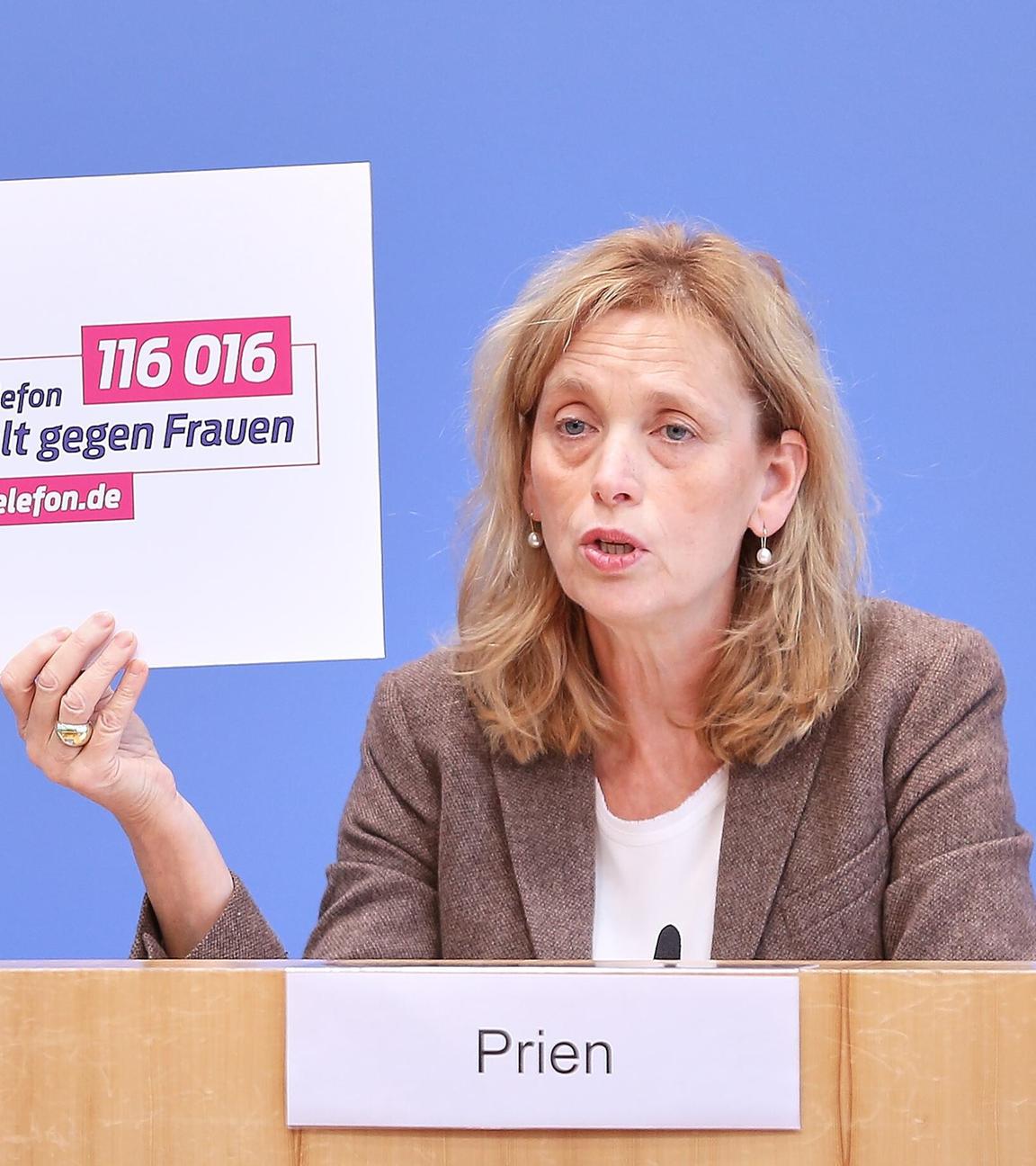 Bundesministerin Prien hält ein Schild auf dem "Gewalt gegen Frauen" steht hinterlegt mit einem Hilfetelefon.