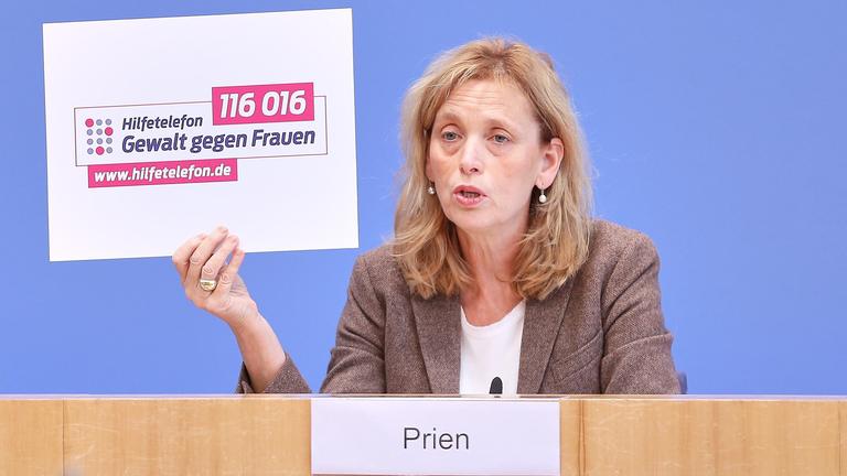 Bundesministerin Prien hält ein Schild auf dem "Gewalt gegen Frauen" steht hinterlegt mit einem Hilfetelefon.