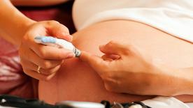 A pregnant woman checks her blood sugar and draws blood from her finger.