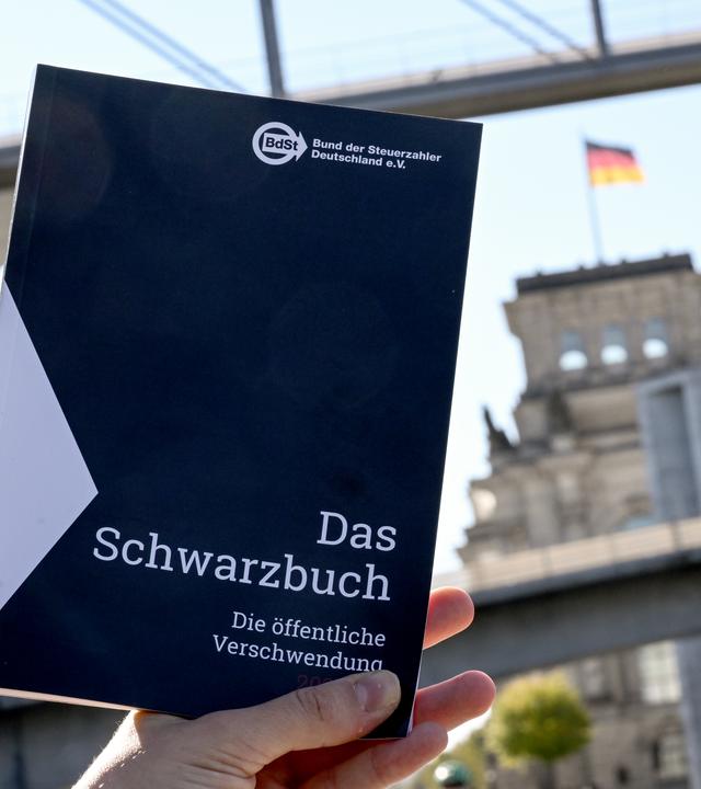 Das Schwarzbuch 2025/26 vom Bund der Steuerzahler Deutschland wird vor das Reichstagsgebäude gehalten. (Archiv)
