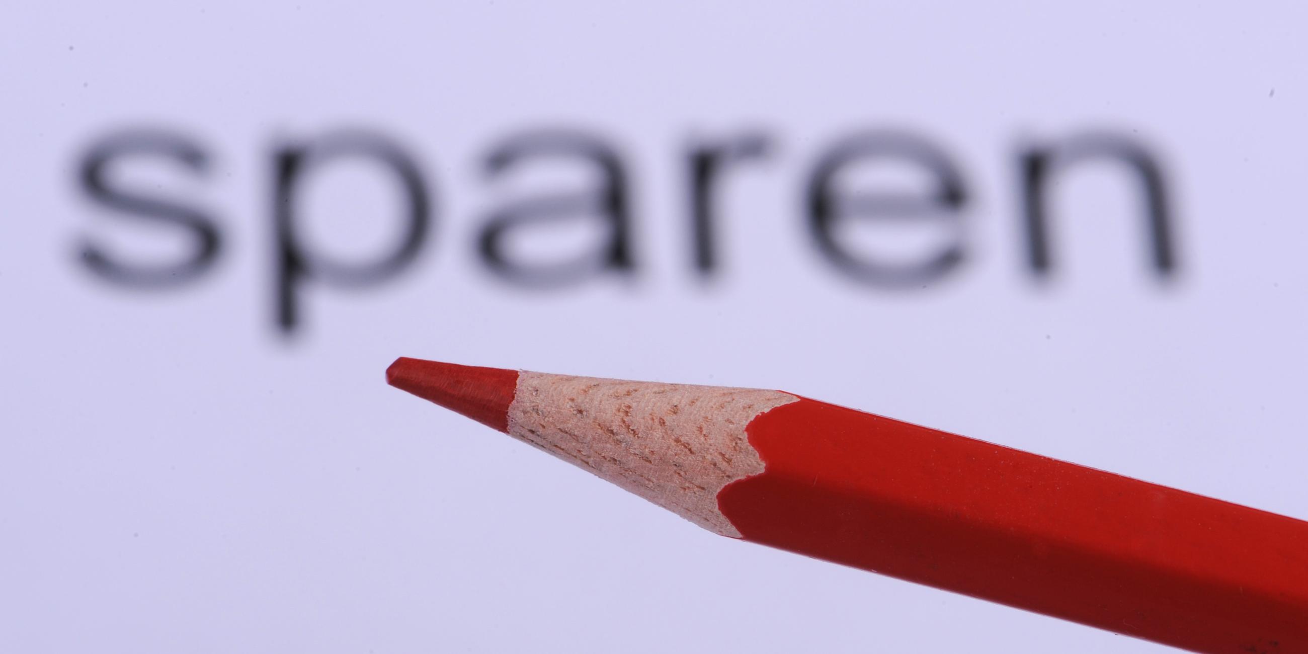Ein Rotstift und das Wort sparen stehen als Symbol für Haushaltseinsparungen. 