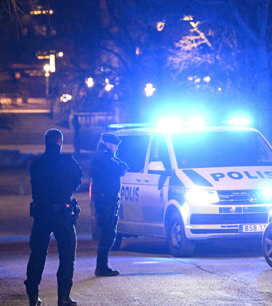 Neben einem schwedischen Polizeiauto stehen Polizisten und eine weitere Person.