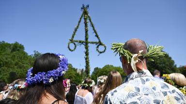 Menschen stehen während der Mittsommerfeierlichkeiten auf der schwedischen Insel Gotland am 20.06.2025 am Mittelbaum.