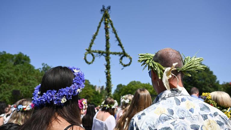 Menschen stehen während der Mittsommerfeierlichkeiten auf der schwedischen Insel Gotland am 20.06.2025 am Mittelbaum.