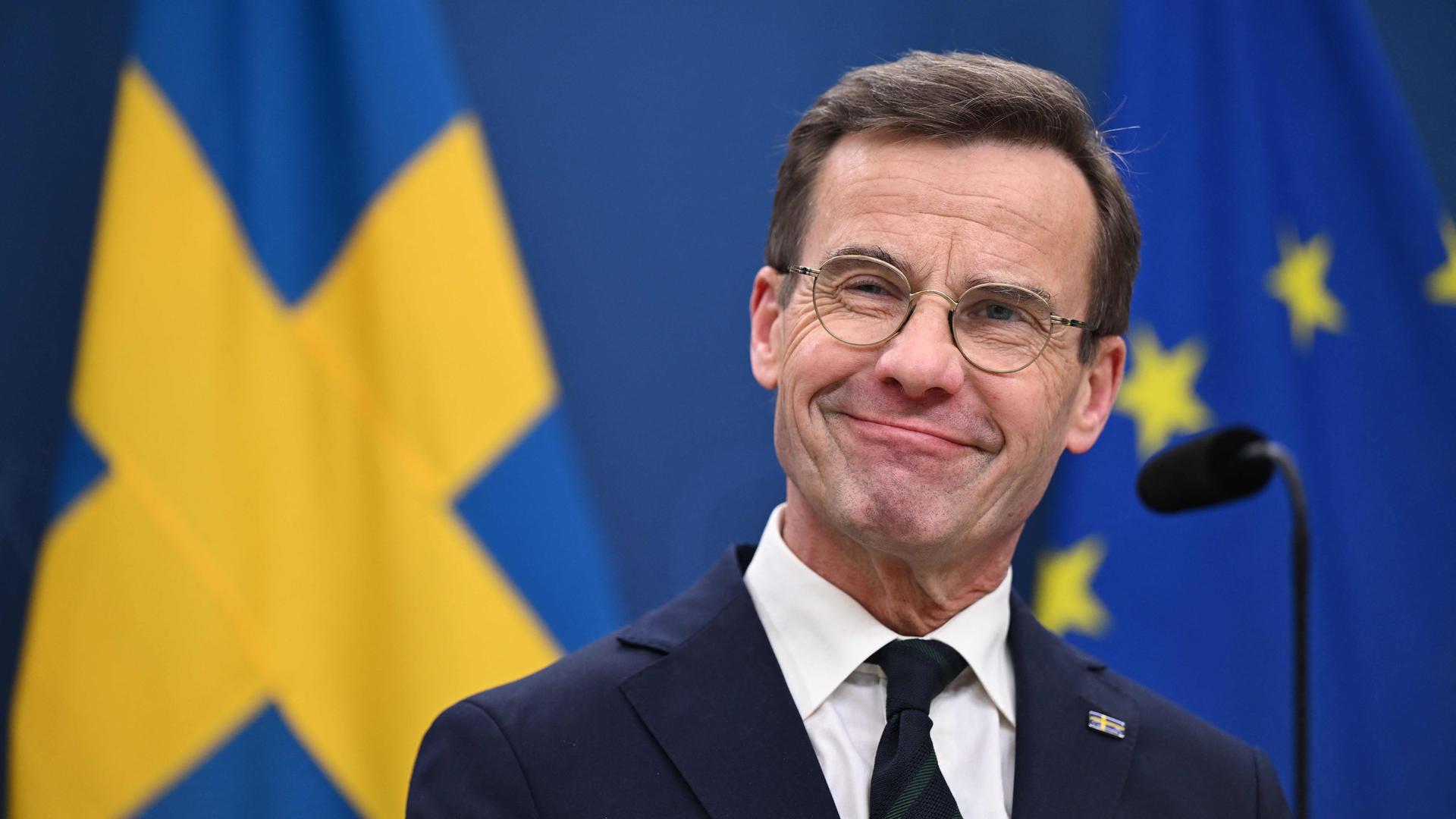 Schwedens Ministerpräsident Kristersson bei einer PK; im Hintergrund Flaggen Schwedens und der EU.