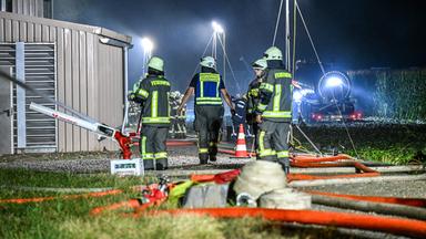 Feuerwehrleute sind beim Brand eines Schweinestalls im Einsatz. bei Brand in Ried, Bayern
