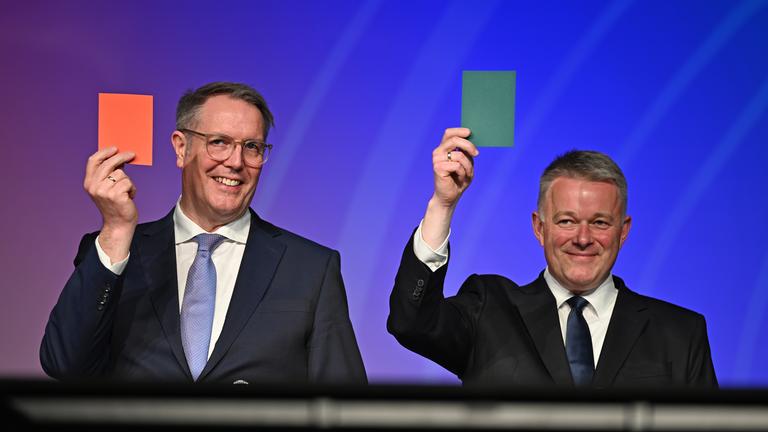 Die beiden Spitzenkandidaten Alexander Schweitzer (SPD, l), Ministerpräsident von Rheinland-Pfalz/Spitzenkandidat seiner Partei, und Gordon Schnieder (CDU), Spitzenkandidat seiner Partei, stehen bei einer Diskussionsrunde der Allgemeinen Zeitung" im Bürgerhaus Lerchenberg in Mainz auf einer Bühne und halten bei einer Fragerunde eine rote und eine grüne Karte hoch. 