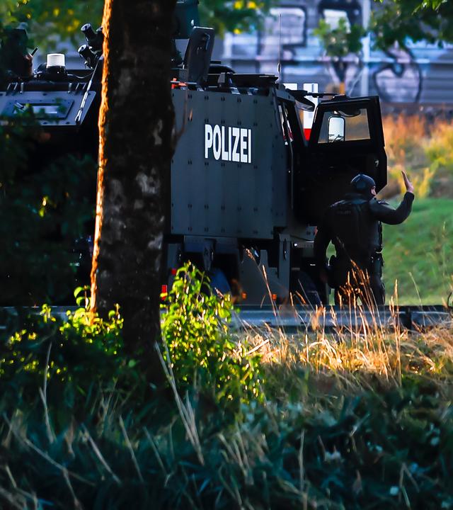 Bewaffnete Polizeibeamte mit einem gepanzerten Einsatzfahrzeug sperren eine Straße in der Nähe der Pferderennbahn Schachen in Aarau ab.