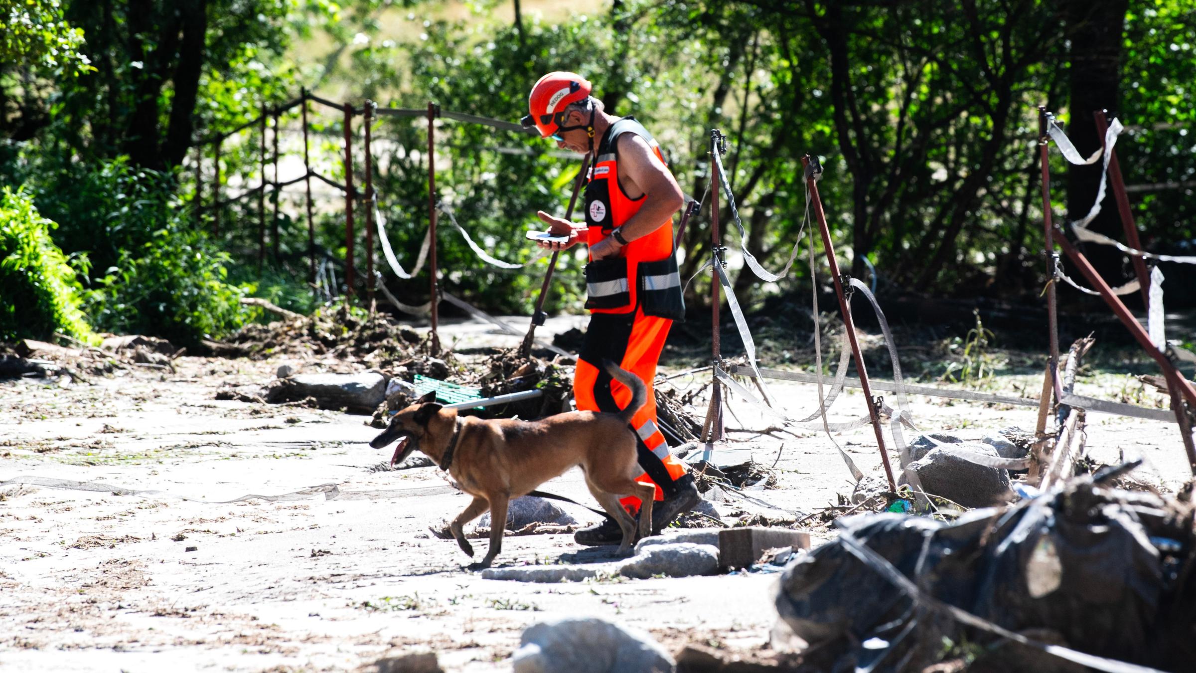 Ein Rettungshelfer geht mit einem Hund während einer Such- und Rettungsaktion an der Stelle eines Erdrutschs spazieren, der durch Unwetter und starken Regen in der Schweiz verursacht wurde.